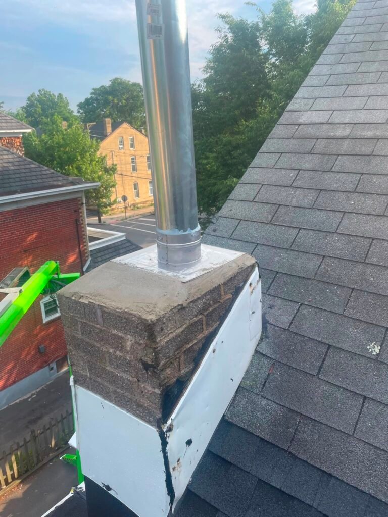 Completed metal chimney-top assembly and cap on the rebuilt chimney base