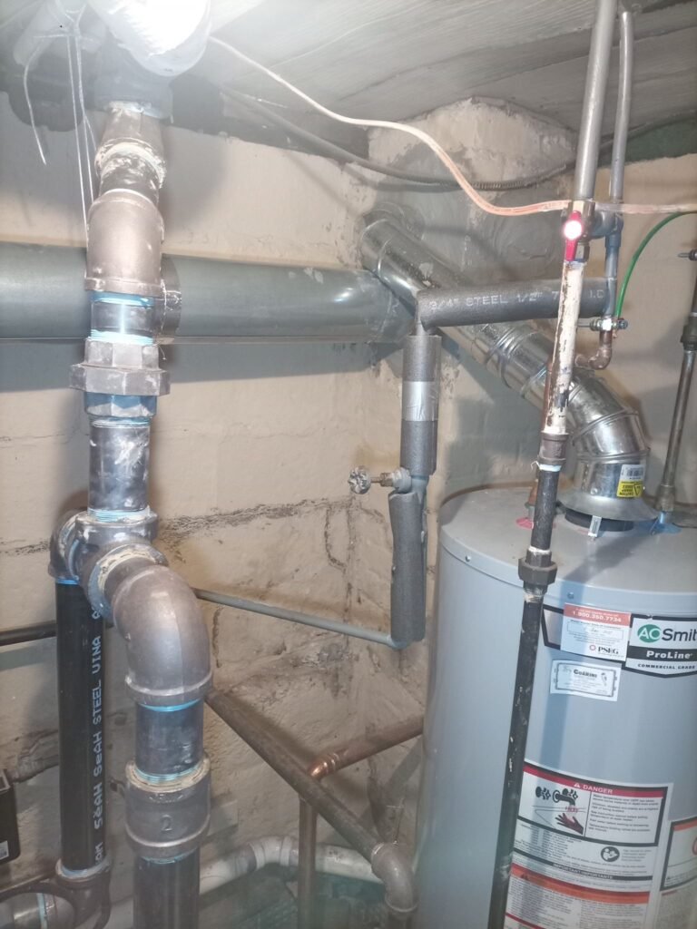 Interior view of a metal chimney liner connection in a basement utility area