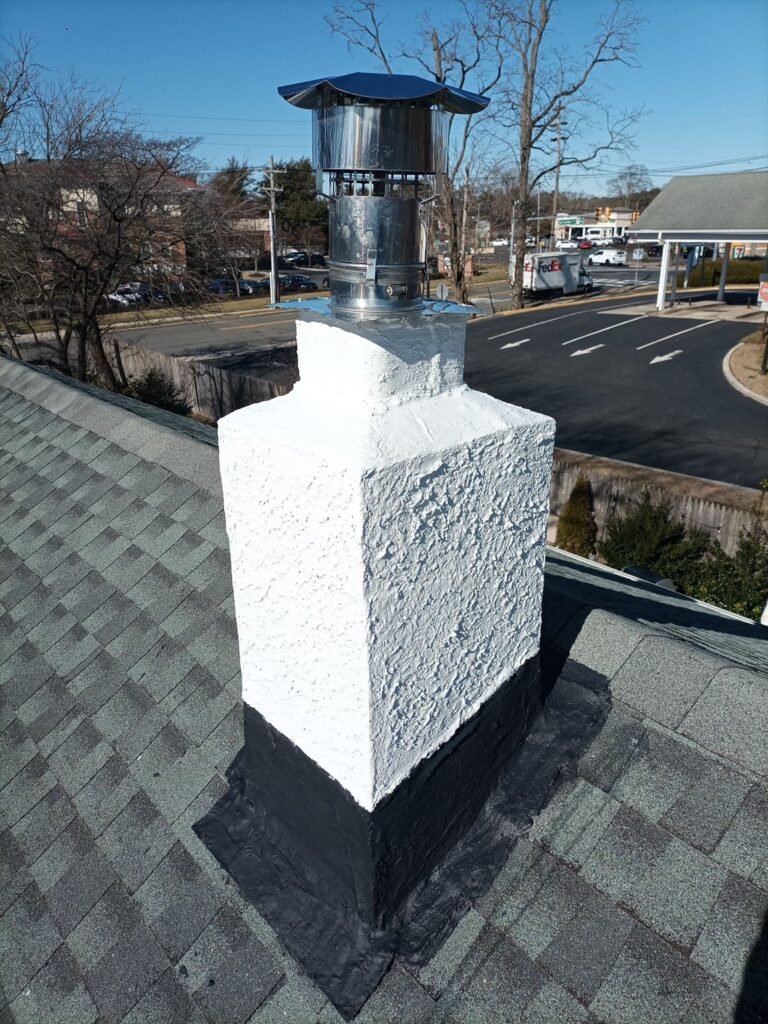 Completed white stucco chimney and cap viewed from the roofline